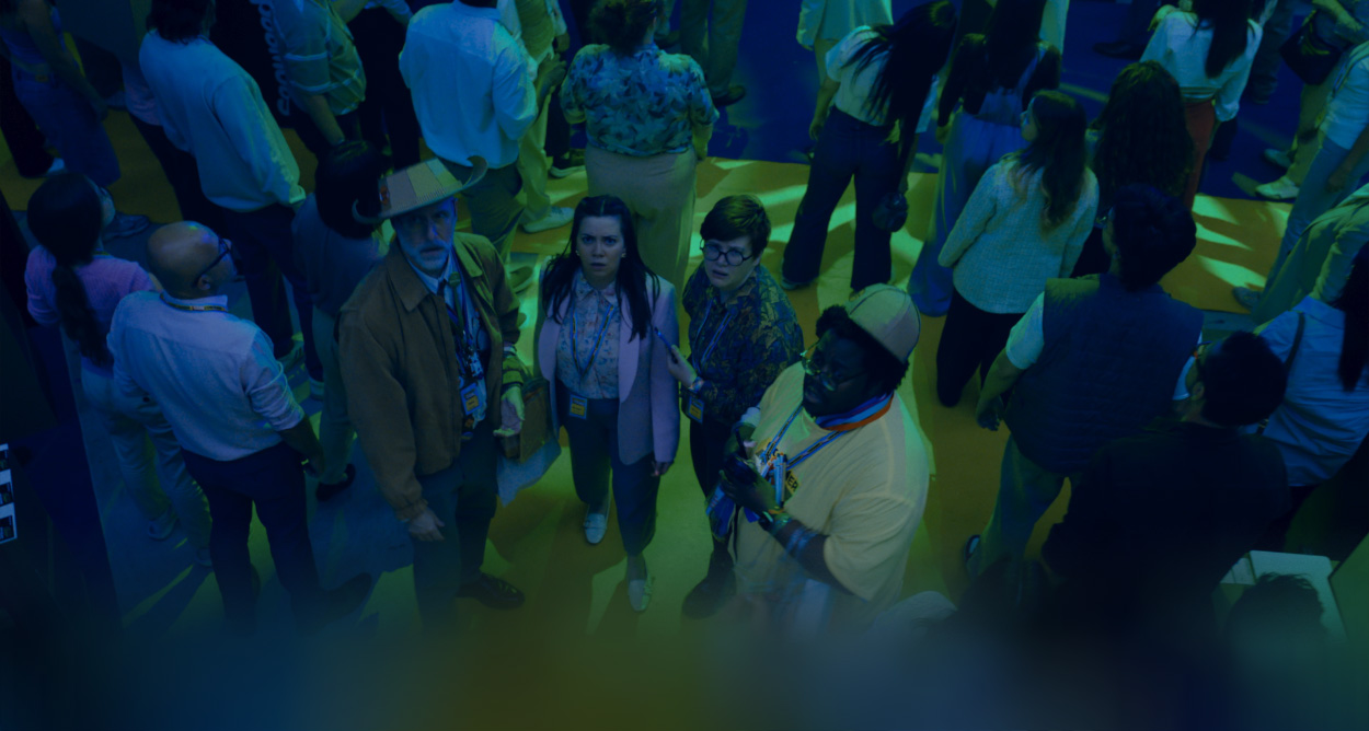 The Underdogs standing together as a group in a crowded convention center, looking up